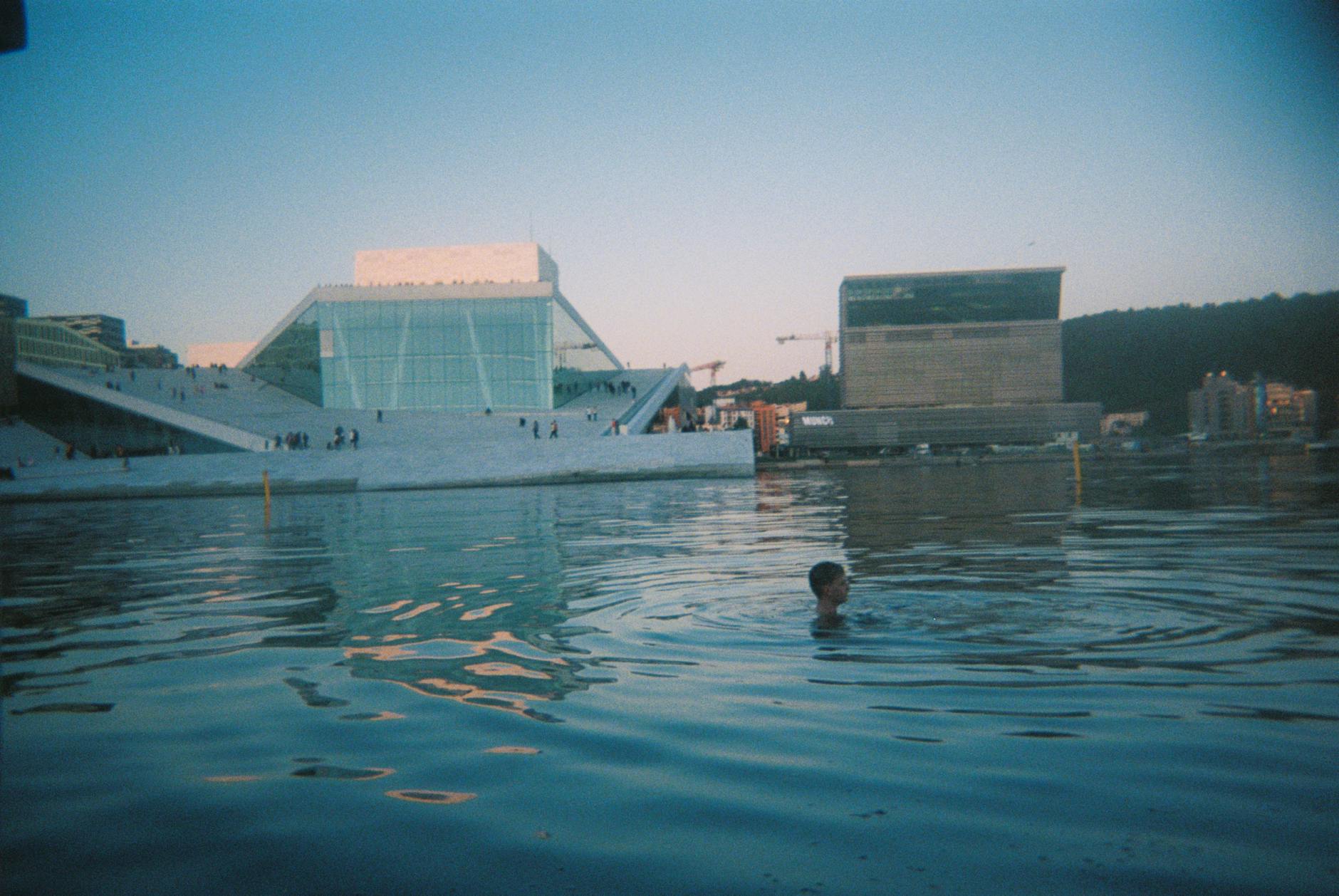 film photo of a person swimming near the oslo opera house